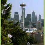 Photo of the Space Needle. Many buildings are in the background. Many trees stand in from of the space needle.