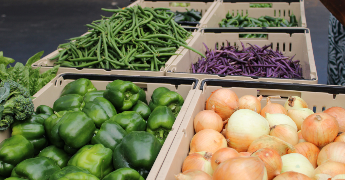 Fresh onions, bell peppers, green beans, and other produce in baskets at the Lake City Farmers Market
