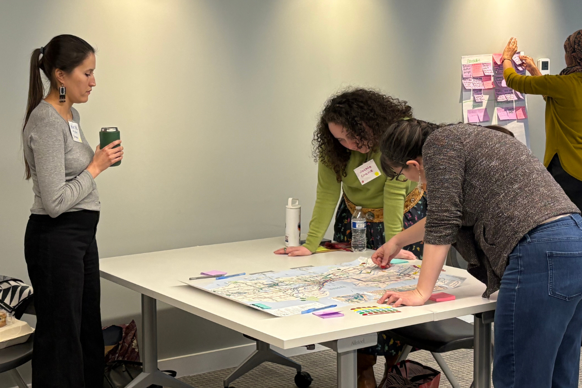 Participants gather around a map laid on a table with stickers, notepads, and pens to mark resources.