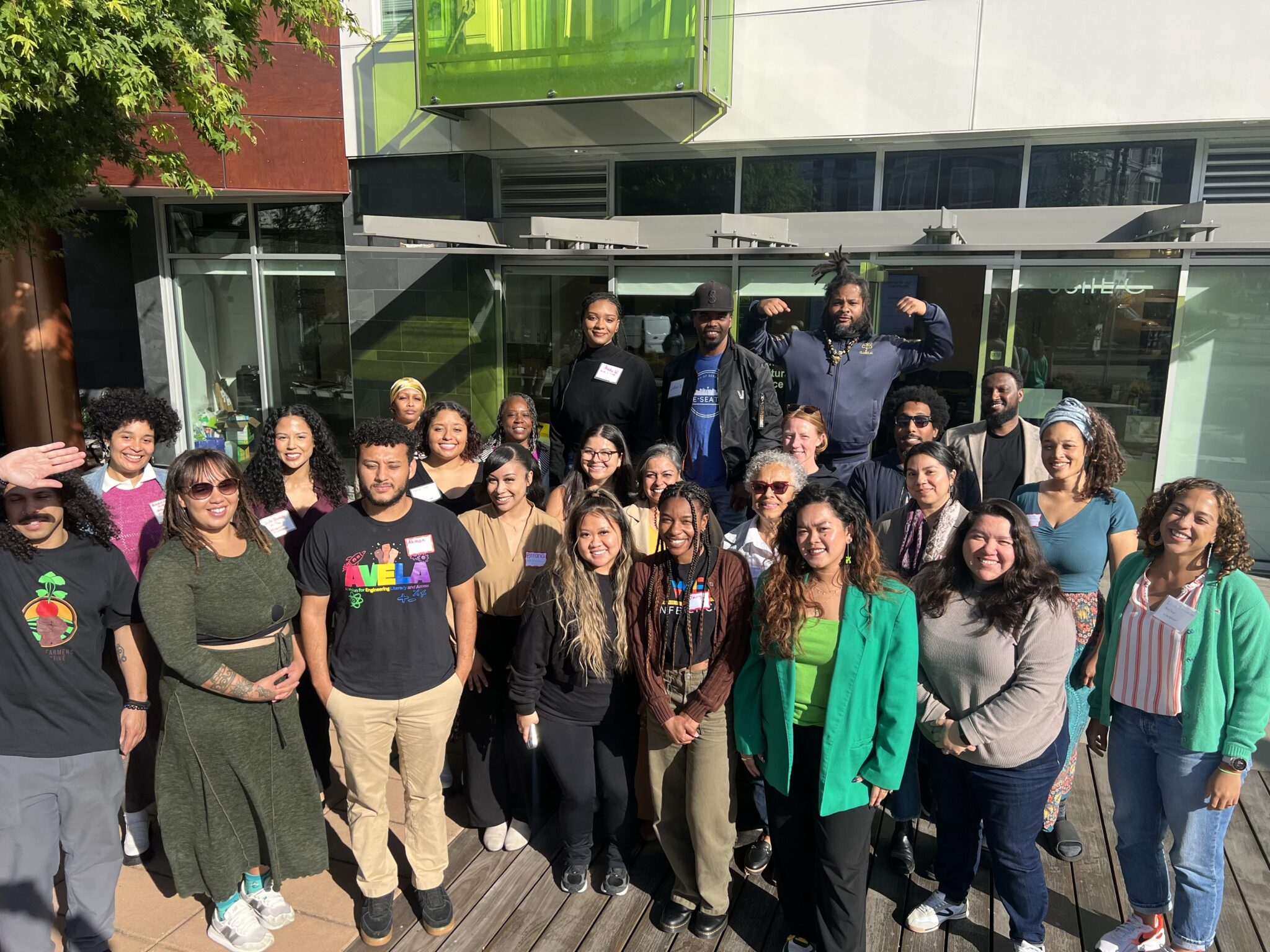 Community Members and OSE staff stand together outdoors in front of a building smiling toward the camera.