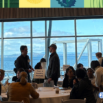 Attendees chat in a conference room overlooking the Puget Sound on a nice day.