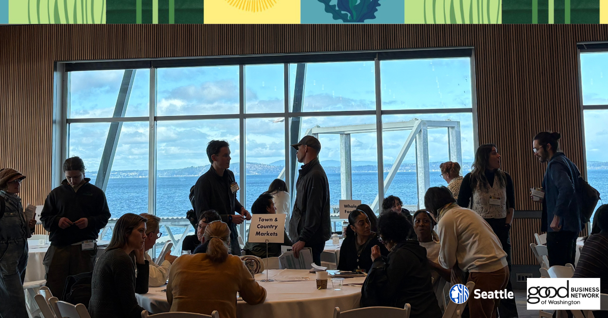 Attendees chat in a conference room overlooking the Puget Sound on a nice day.
