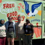 Four people stand smiling in front of a green food truck offering free mobile food pantry services with colorful artwork and a bird illustration.