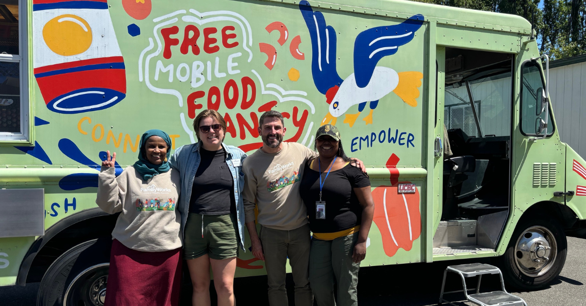 Four people stand smiling in front of a green food truck offering free mobile food pantry services with colorful artwork and a bird illustration.