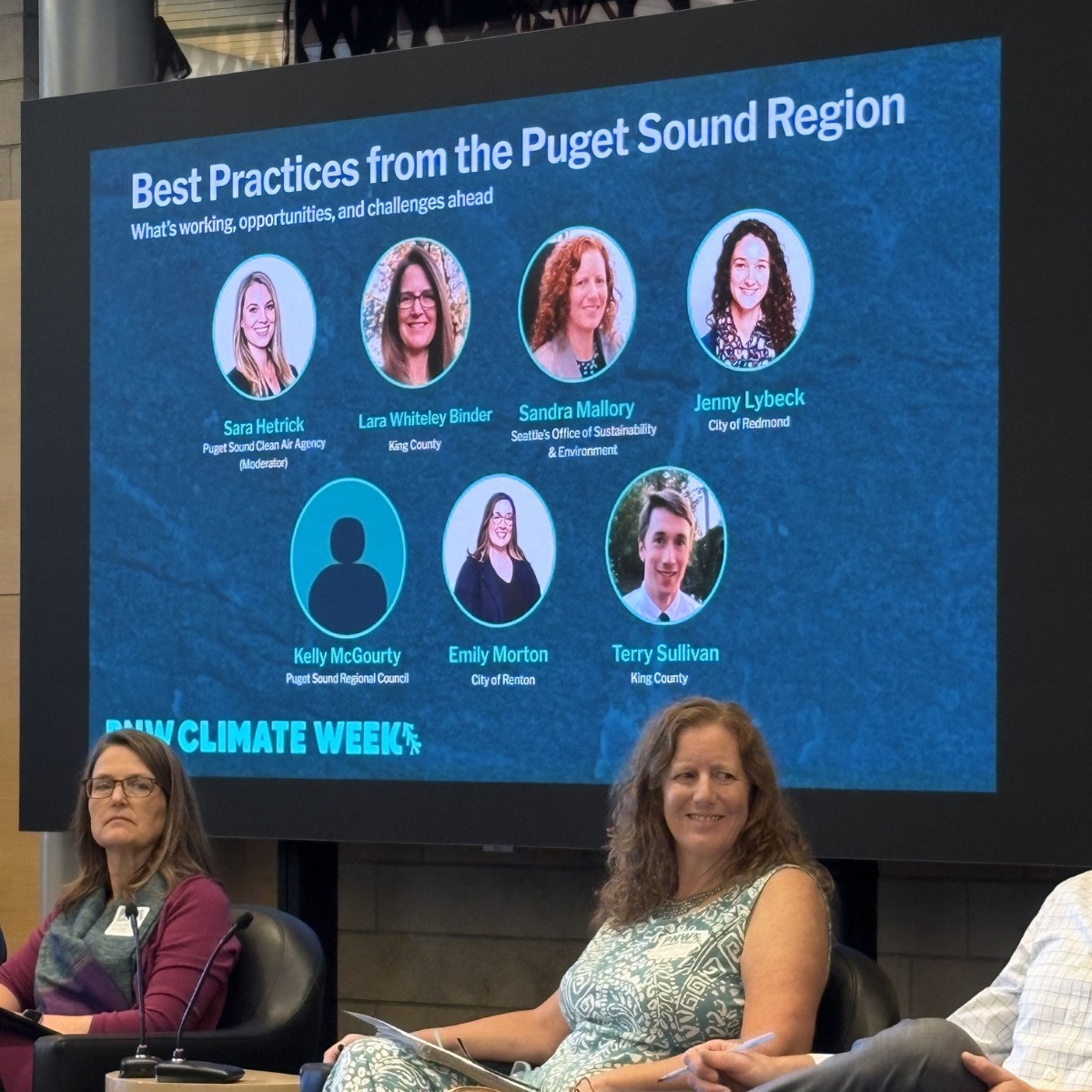 Sandra Mallory seated in front of a large screen displaying PNW Climate Week panel speakers.