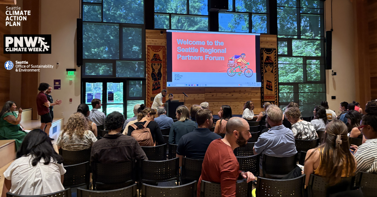 An audience seated in a wood-paneled room facing a large screen reading ‘Welcome to the Seattle Regional Partners Forum.’
