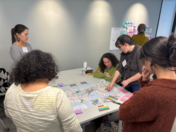 Participants stand around a table with map of Seattle during a group activity.